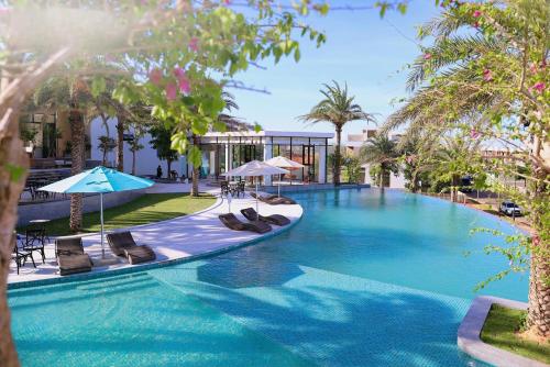 a large swimming pool with chairs and umbrellas at Villa 4 phòng ngủ tại NovaWorld Phan Thiết in Bình Tú