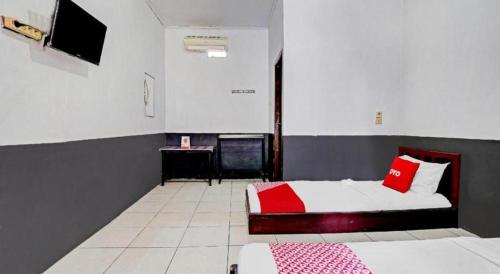 a room with two beds and a flat screen tv at OYO 90405 Penginapan Sasti Kuningan in Kuningan