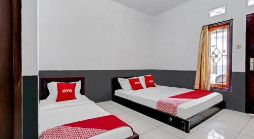 two beds in a room with red and white pillows at OYO 90405 Penginapan Sasti Kuningan in Kuningan