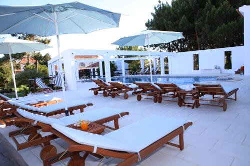 a group of chairs and umbrellas next to a pool at Vila Louro in Santa Cruz