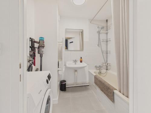 a white bathroom with a sink and a bath tub at Appartement avec piscine commune pour 4 in Guérande