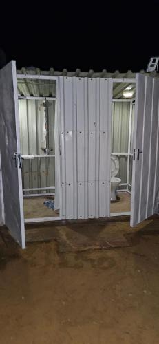 a group of white doors in a room with a toilet at The Kimberlite Camping & Caravan Parking, Jwaneng in Jwaneng
