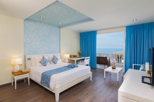 a bedroom with a bed and a balcony with the ocean at The Cliff Resort & Residences in Mui Ne