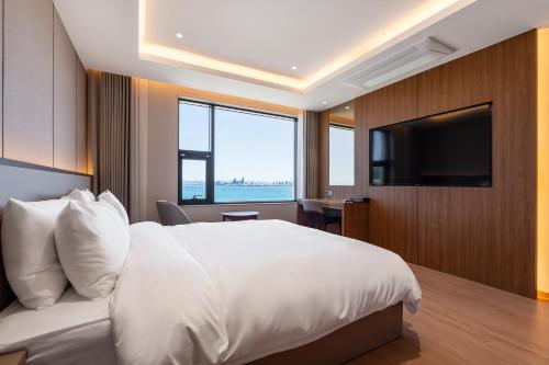 a bedroom with a large white bed and a flat screen tv at Pohang Yeongildae Beach Hotel in Pohang