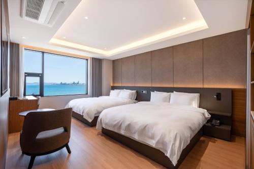a hotel room with two beds and a chair at Pohang Yeongildae Beach Hotel in Pohang