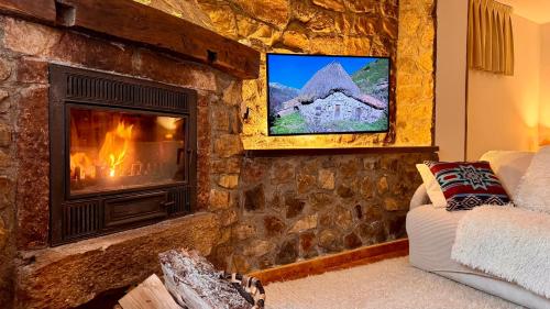 sala de estar con chimenea de piedra y TV en Apartamentos y Casas de Aldea La Pornacal, en Villar de Vildas