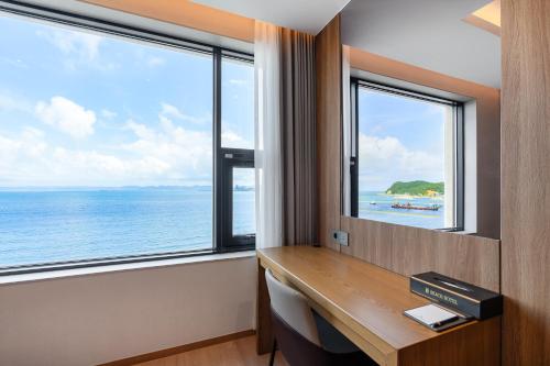 a room with a desk with a view of the ocean at Pohang Yeongildae Beach Hotel in Pohang
