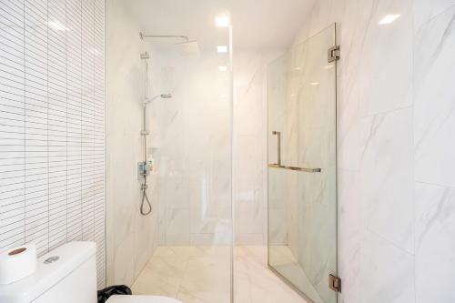 a white bathroom with a shower and a toilet at Hyde Sukhumvit 11 Bangkok in Bangkok