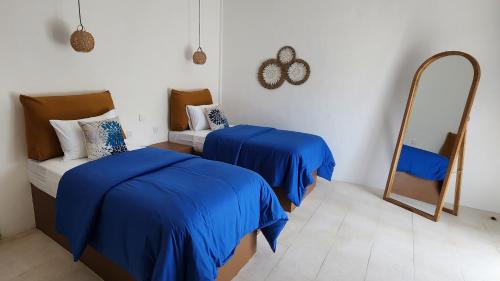 a bedroom with two beds with blue sheets and a mirror at Mocean Beach Resort in Lemonga