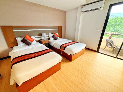 a hotel room with two beds and a balcony at Swimming Pool Apartment Hotel in Patong Beach