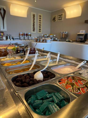 a buffet line with many different foods and spoons at Hotel La Perla Del Golfo in Procchio