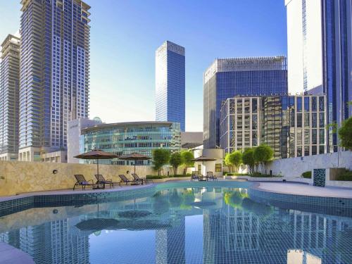 a large swimming pool in a city with tall buildings at Novotel Kuala Lumpur City Centre in Kuala Lumpur