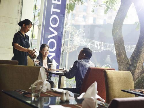 three people sitting at a table in a restaurant at Novotel Kuala Lumpur City Centre in Kuala Lumpur