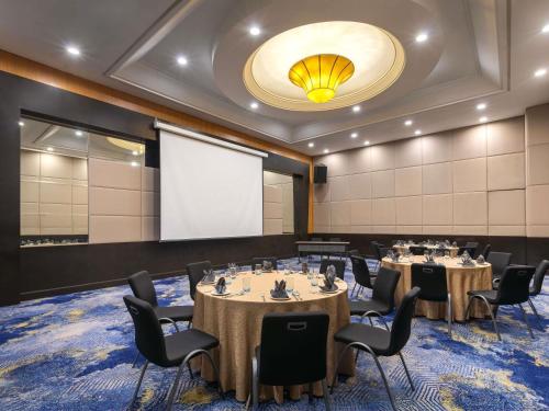 a conference room with tables and chairs and a projection screen at Novotel Kuala Lumpur City Centre in Kuala Lumpur
