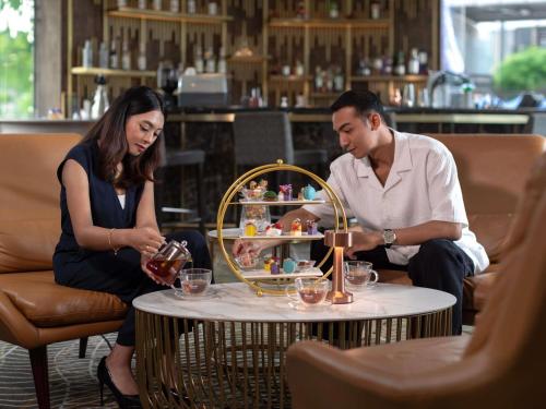 a man and a woman sitting around a coffee table at Novotel Kuala Lumpur City Centre in Kuala Lumpur