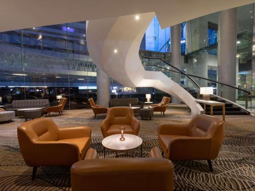 a lobby with chairs and tables and a staircase at Novotel Kuala Lumpur City Centre in Kuala Lumpur