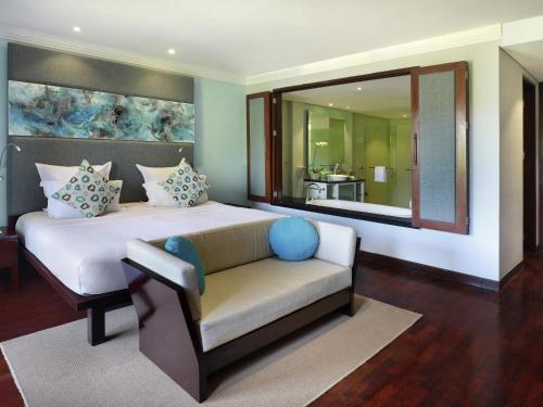 a bedroom with a bed and a couch and a mirror at Novotel Bali Nusa Dua in Nusa Dua