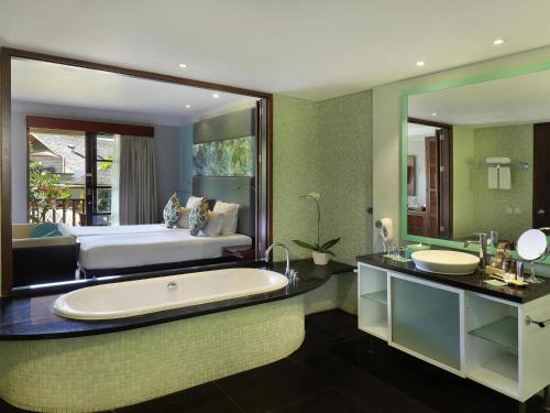a bathroom with a large tub and a bed at Novotel Bali Nusa Dua in Nusa Dua