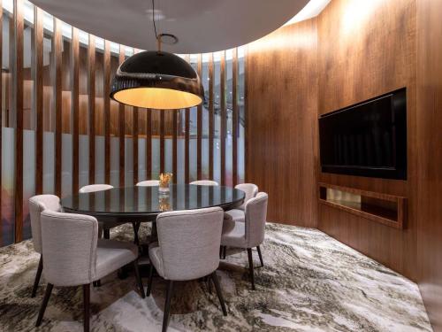 a dining room with a table and chairs and a television at Novotel Kuala Lumpur City Centre in Kuala Lumpur