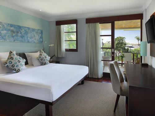 a bedroom with a large white bed and a balcony at Novotel Bali Nusa Dua in Nusa Dua