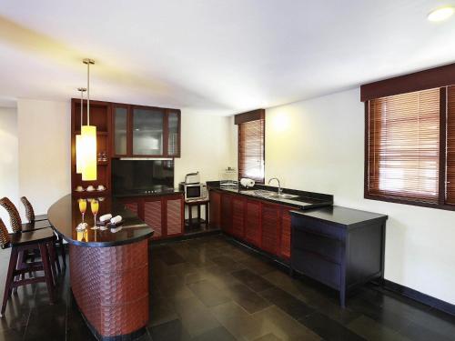 a kitchen with wooden cabinets and a counter top at Novotel Bali Nusa Dua in Nusa Dua