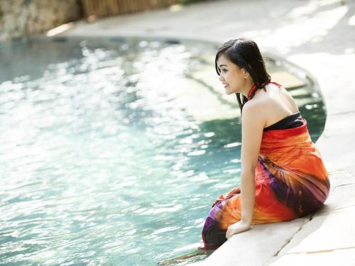 a woman sitting next to a swimming pool at Novotel Bali Nusa Dua in Nusa Dua