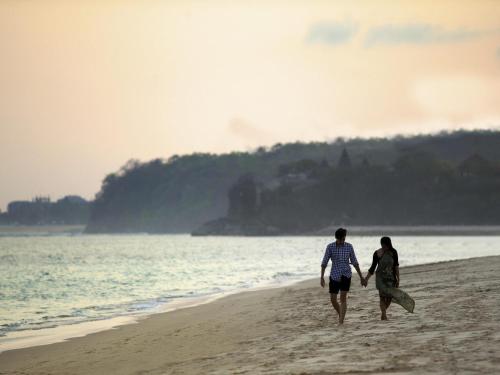 a man and woman walking on the beach at Novotel Bali Nusa Dua in Nusa Dua