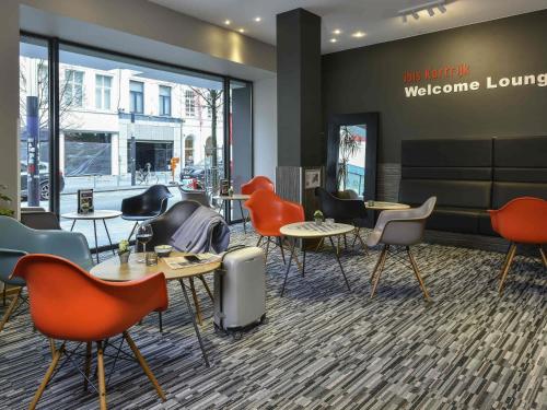 a waiting room with tables and chairs and a welcome lounge at ibis Kortrijk Centrum in Kortrijk