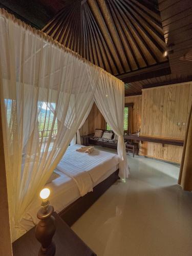 a bedroom with a bed with a mosquito net at Puri Alam Bali in Munduk