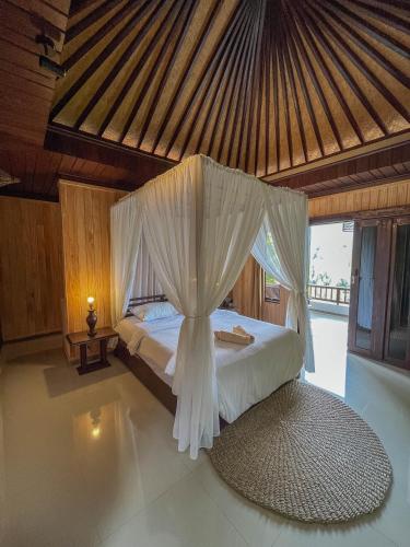 a bedroom with a bed with a mosquito net at Puri Alam Bali in Munduk