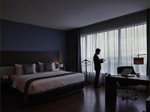 a man standing in a hotel room looking out the window at Pullman Kuching in Kuching