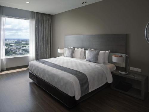 a bedroom with a large bed and a large window at Pullman Kuching in Kuching