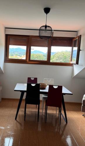 una sala da pranzo con tavolo, sedie e finestre di Aldea Bricia 6 a Posada de Llanes