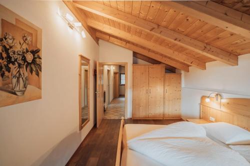 a bedroom with a large bed and wooden ceilings at Oberegghof Ferienwohnung Hahnenkamm in Rifiano
