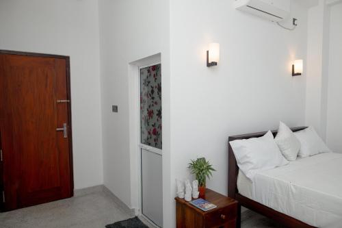 a bedroom with a bed and a wooden door at Buddy's Place in Ambalangoda
