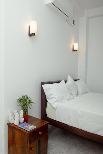 a bedroom with a bed and a nightstand with a table at Buddy's Place in Ambalangoda