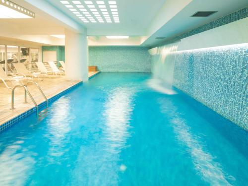 a swimming pool with blue water in a building at Novotel Lima San Isidro in Lima