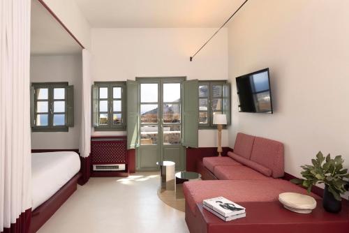 a living room with a bed and a couch and a tv at Neema Maison Finikia Santorini in Oia