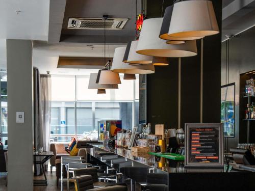 a restaurant with a bar with chairs and lights at Novotel Lima San Isidro in Lima