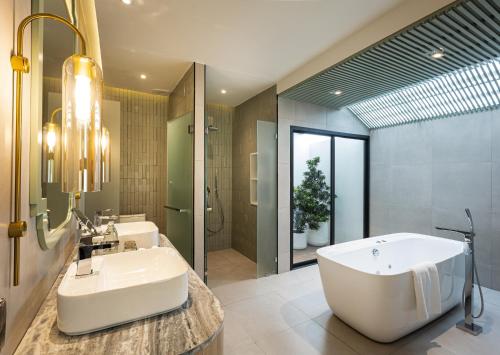 a bathroom with a large tub and a sink at La Solaya Khao Lak in Khao Lak