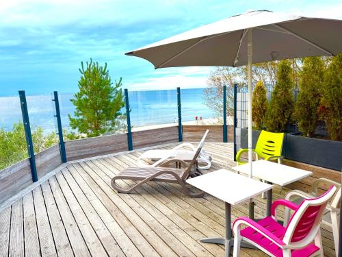 a deck with chairs and a table and an umbrella at Apartamenty i Domki WyDmy Międzywodzie in Międzywodzie