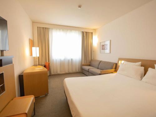 a hotel room with a bed and a couch at Novotel Salerno Est Arechi in Salerno