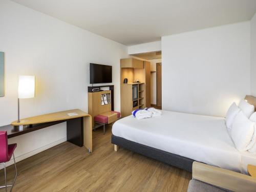 a hotel room with a large bed and a desk at Novotel Salerno Est Arechi in Salerno