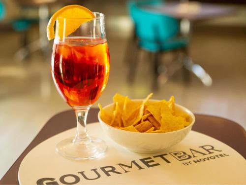 a drink and a bowl of chips on a tray at Novotel Salerno Est Arechi in Salerno