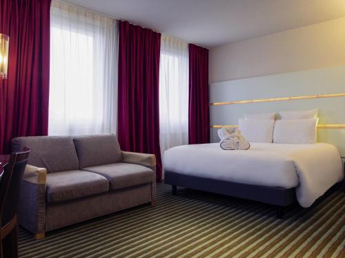 a hotel room with a bed and a chair at Mercure Paris Ivry Quai De Seine in Ivry-sur-Seine
