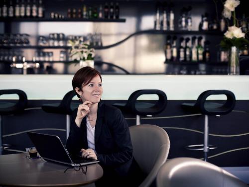 a woman sitting at a table with a laptop at Mercure Paris Ivry Quai De Seine in Ivry-sur-Seine