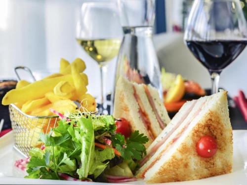 a plate of food with a sandwich and a glass of wine at Mercure Paris Ivry Quai De Seine in Ivry-sur-Seine