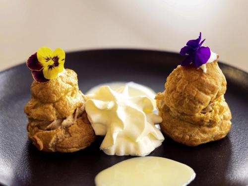 a black plate with three cookies and a flower on it at Mercure Paris Ivry Quai De Seine in Ivry-sur-Seine