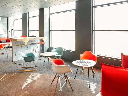 a room with colorful chairs and tables and windows at ibis Birmingham Airport Terminal Building - NEC in Bickenhill