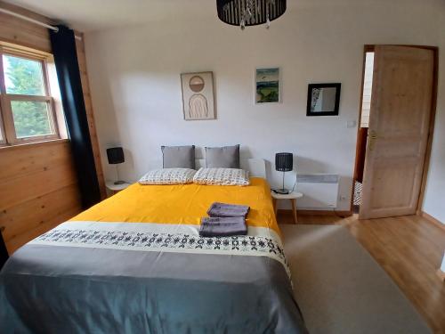 a bedroom with a large bed with a yellow blanket at Ma Cabane du Canada in Combray
